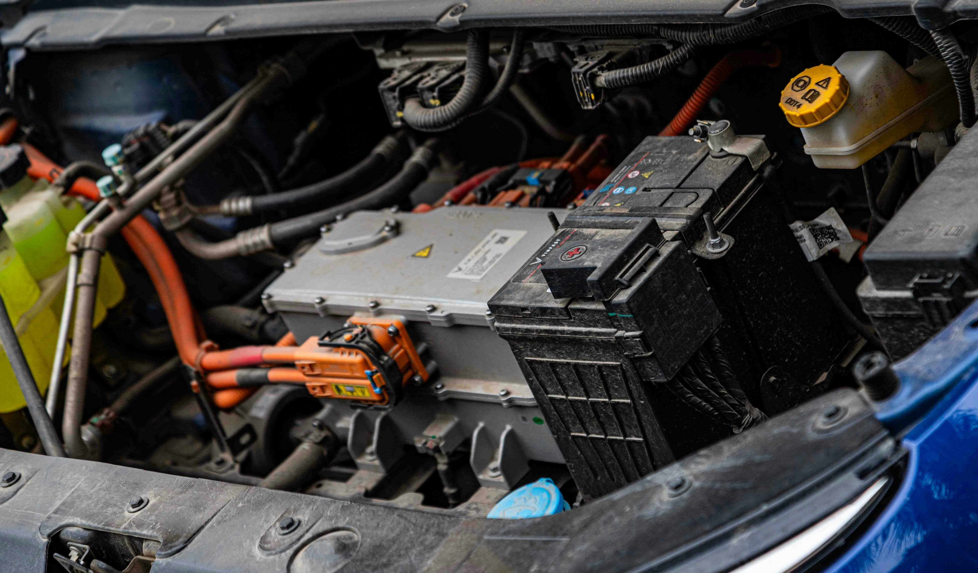A picture of the engine bay of an hybrid vehicle, showing a battery and connectors